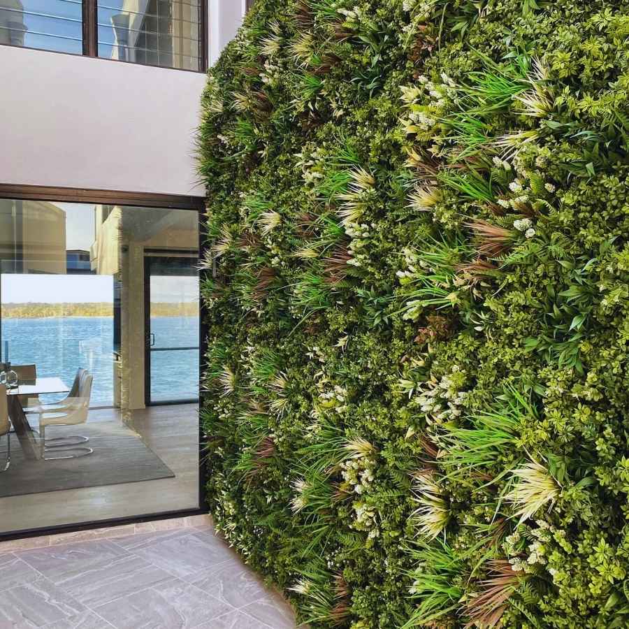 Artificial green wall installed in modern residential interior next to glass doors as decorative accent wall