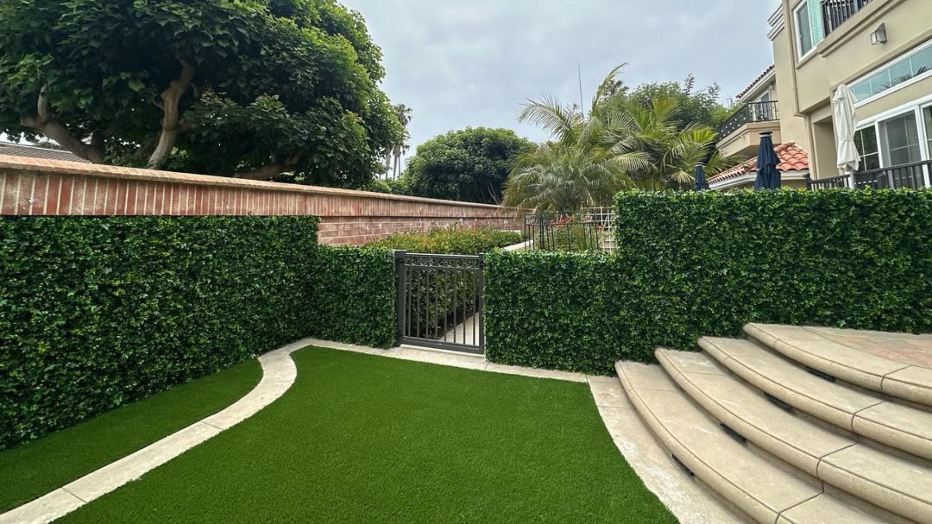 Outdoor backyard with artificial green wall panels 40x40 creating a UV-protected privacy hedge, weather resistant and maintenance-free