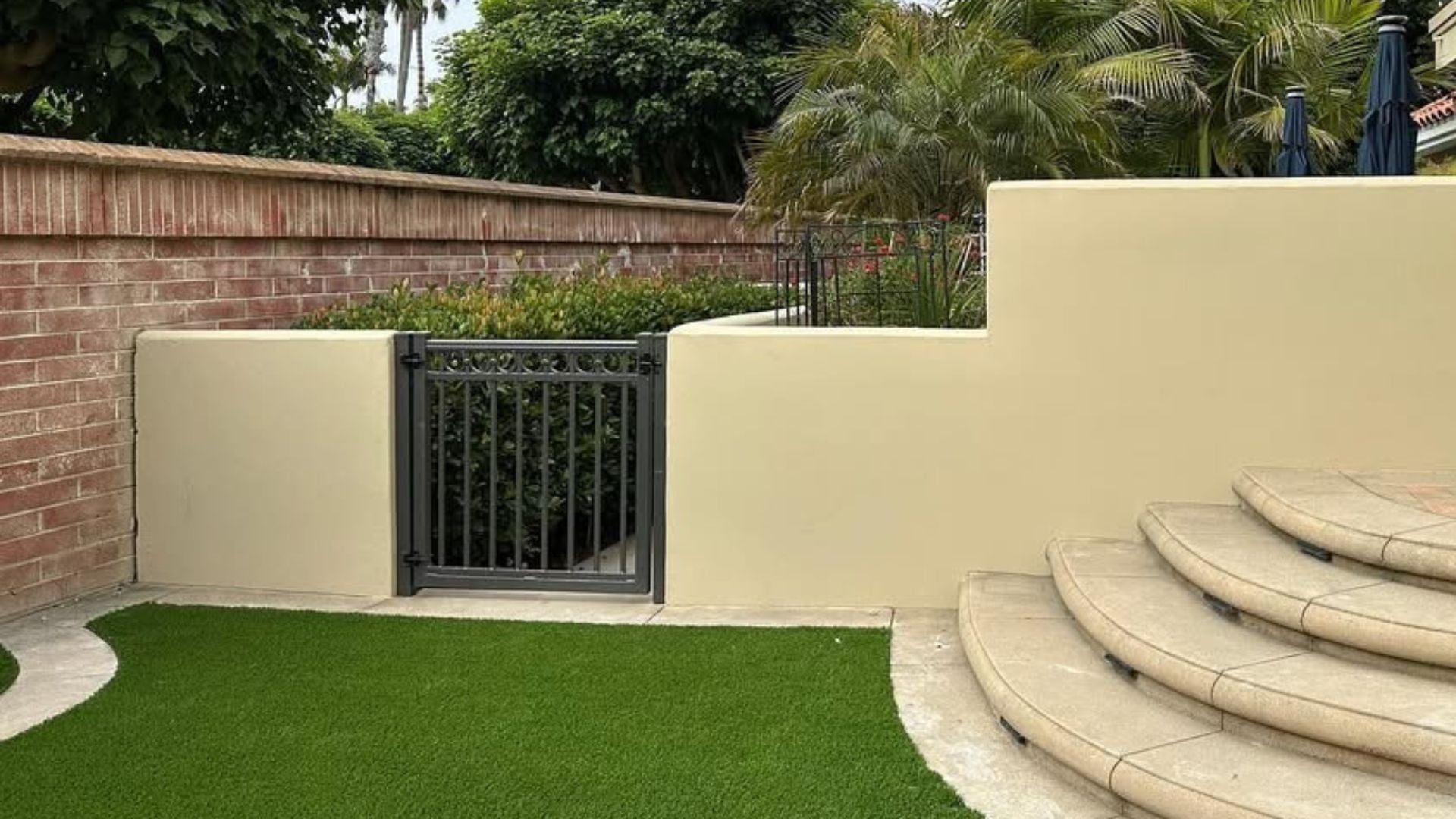 Outdoor backyard wall and gate area without artificial green wall panels showing plain beige fence and brick wall background