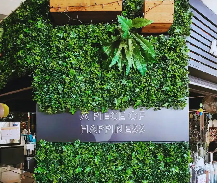 Artificial green wall installed in commercial space with custom signage used as decorative feature wall in retail environment