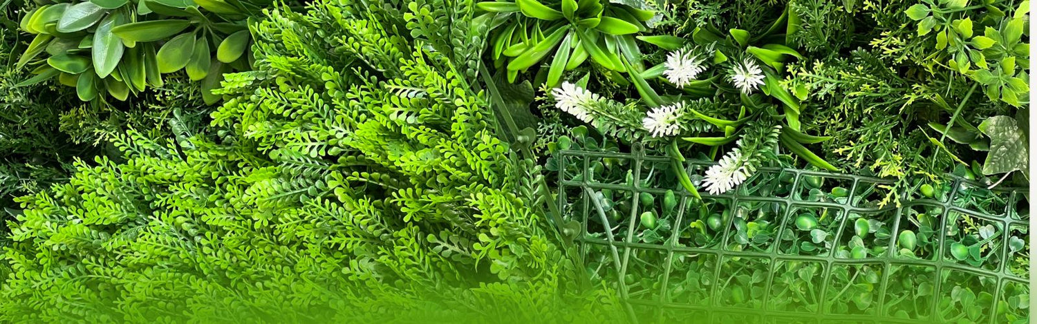 artificial green wall panels featuring mixed foliage textures, including boxwood, ferns, and white accent flowers, mounted on a green plastic mesh grid for modular installation