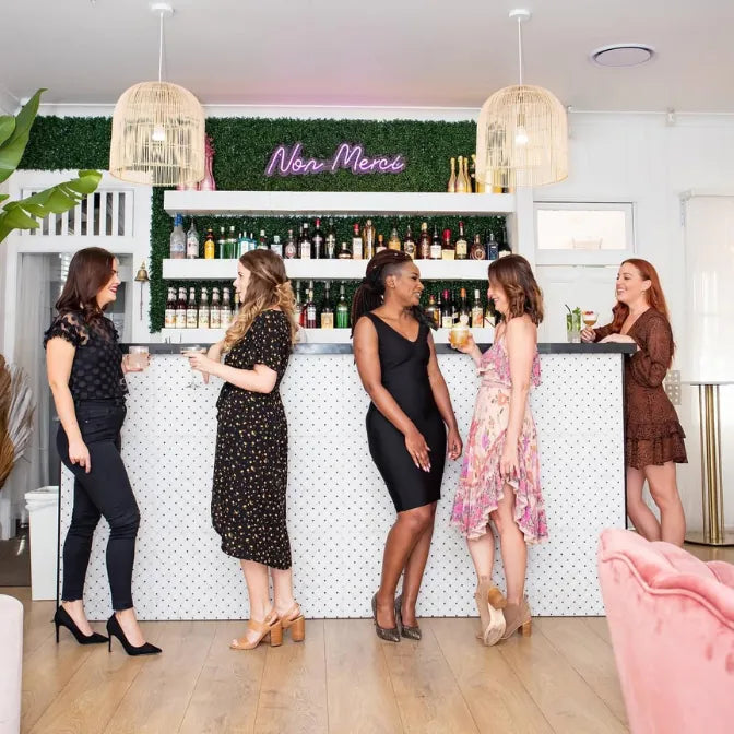 Trendy bar interior with artificial boxwood green wall panels and neon sign creating stylish backdrop for social gatherings