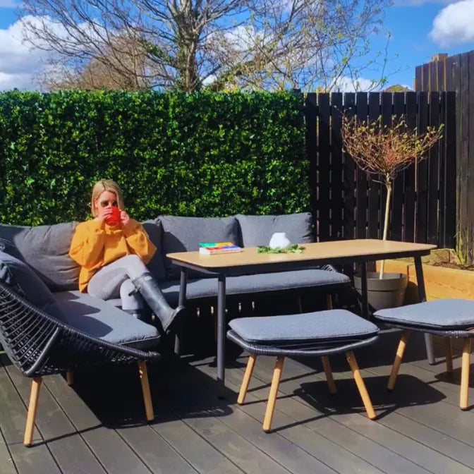 Outdoor patio with artificial green wall panels used as vertical garden privacy hedge behind modern furniture set
