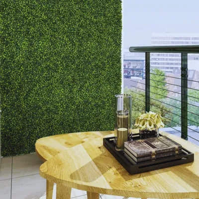 Balcony with artificial hedge wall panel and wooden table – UV-protected greenery wall for privacy and modern decor
