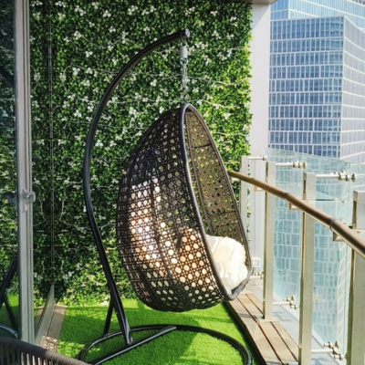 Modern balcony with artificial green wall panels and hanging chair – UV-protected vertical garden for outdoor privacy and stylish home decor