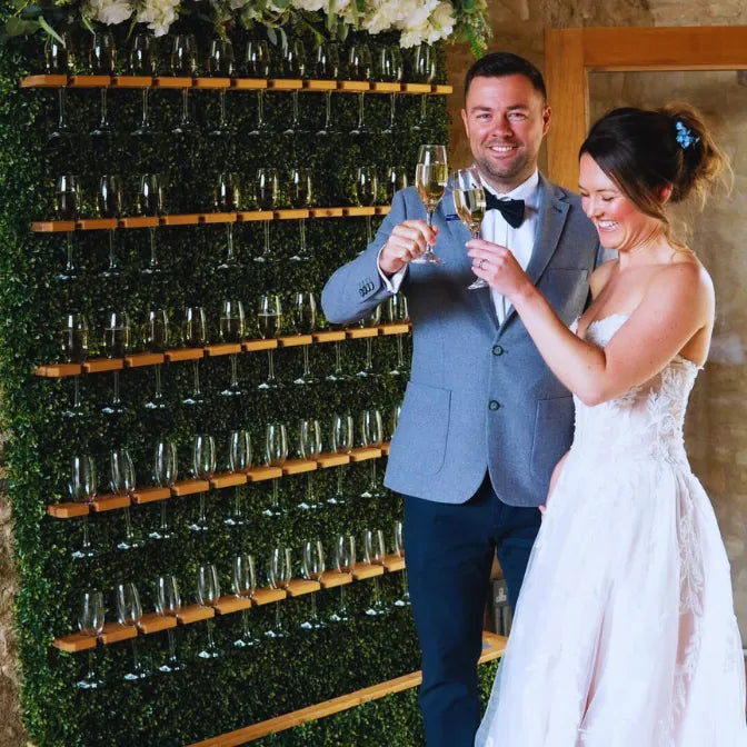 Wedding champagne wall made of artificial boxwood backdrop panels with glass holders, creating elegant greenery decor for events and receptions