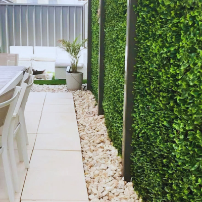 Outdoor patio with Gardenia Leaf Artificial Hedge Wall Panels 40"x40" by Green Warehouse, glossy greenery for privacy fences and modern decor