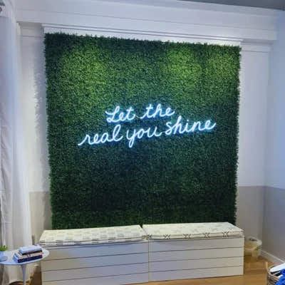 Artificial boxwood green wall installed in modern interior with neon sign used as decorative feature wall