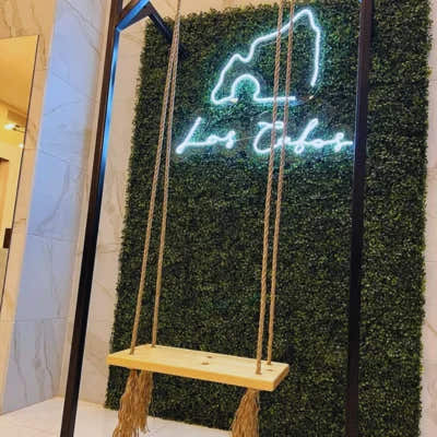 Artificial boxwood green wall installed in modern interior with neon sign and swing used as decorative feature wall
