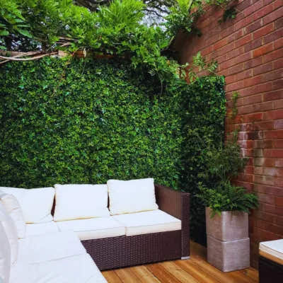 Patio with faux plant wall panel and wicker sofa – UV-protected artificial hedge for outdoor privacy and modern decor